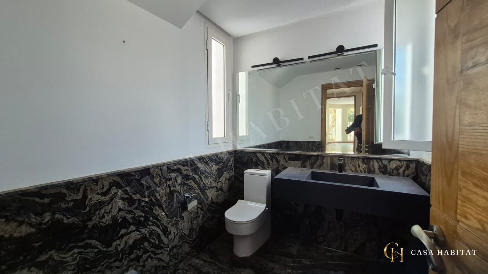 Salle d'eau avec plan vasque noir et murs en marbre sombre