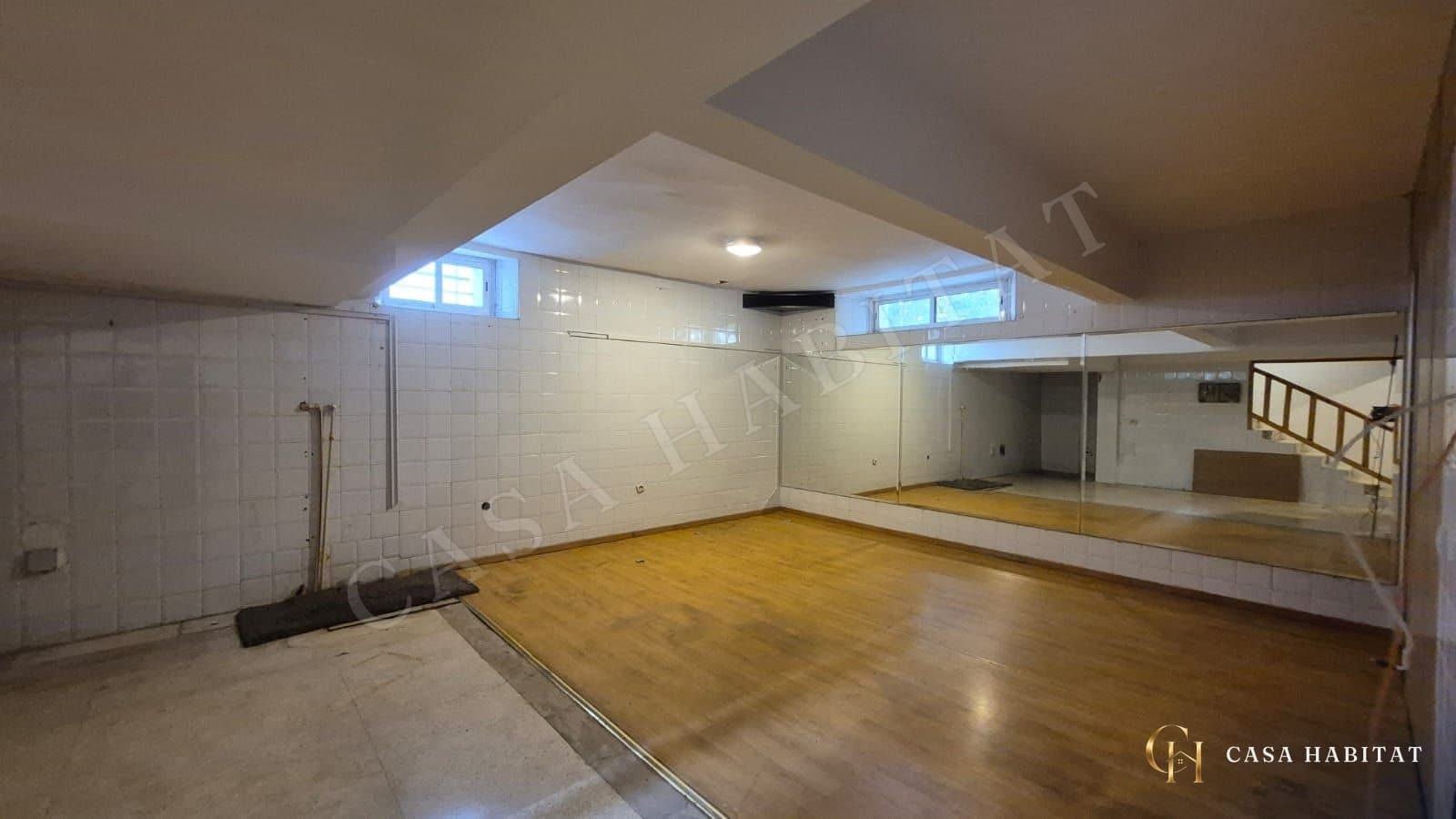 Salle de sport au sol en parquet avec miroirs muraux et carrelage blanc