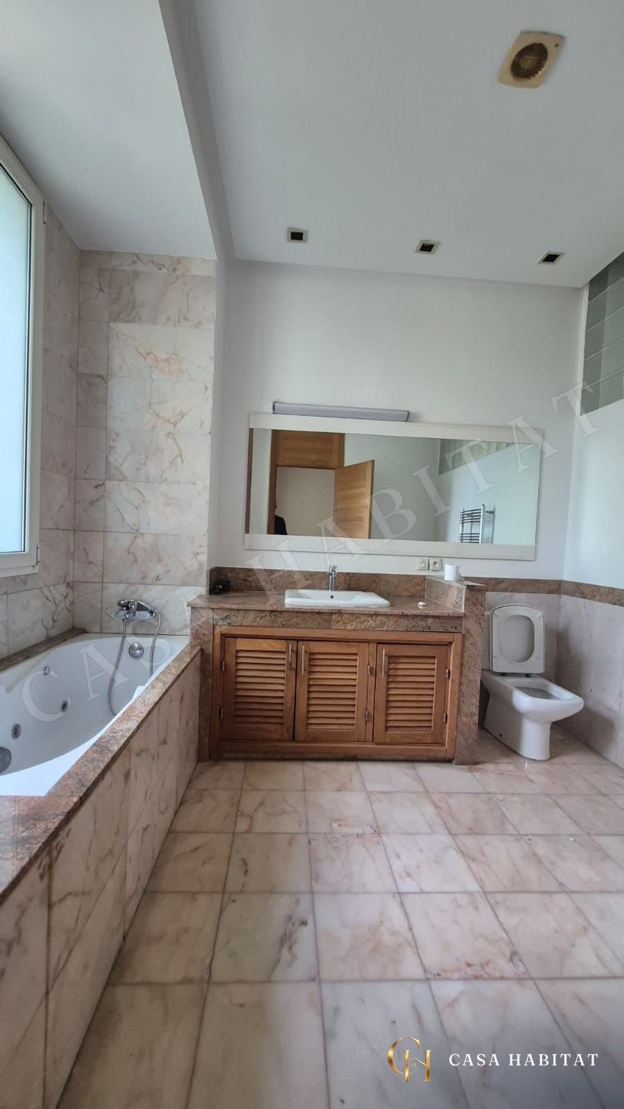 Salle de bain avec baignoire d'angle, double vasque en bois et WC