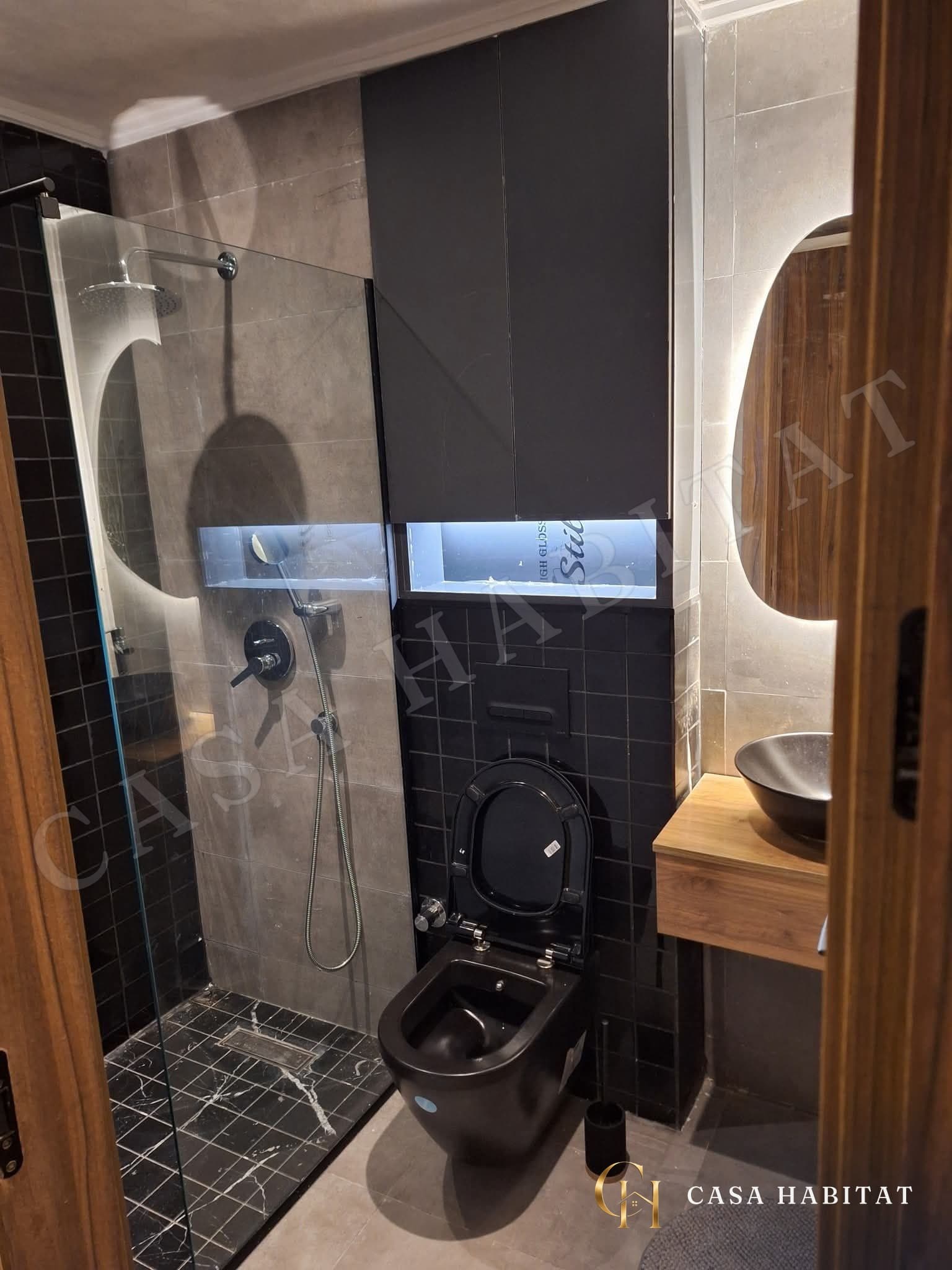 Salle de bain avec douche à l'italienne, WC noirs et vasque
