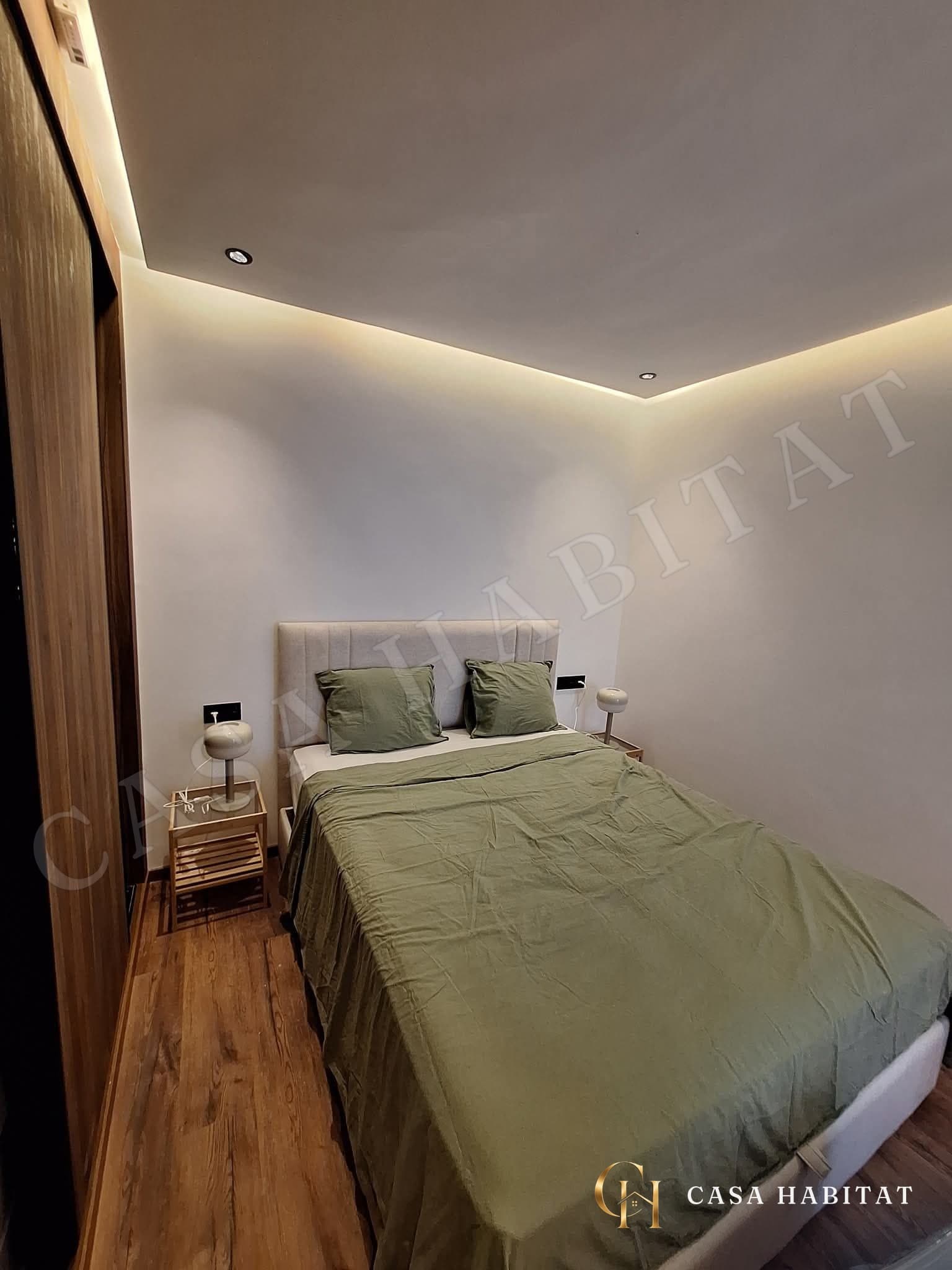 Chambre avec lit recouvert de linge vert et tables de chevet