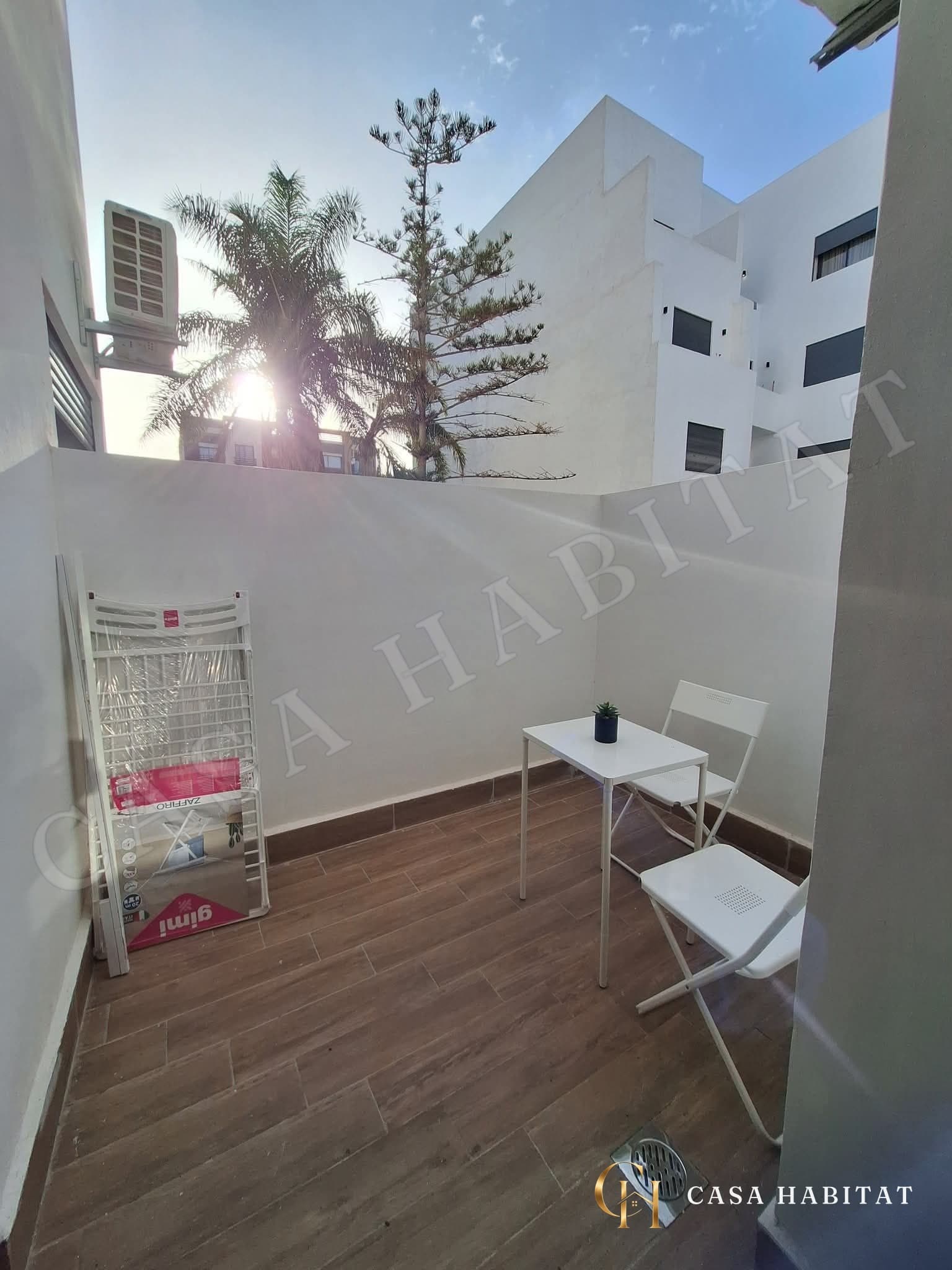 Terrasse carrelée avec petite table et chaises blanches pliantes