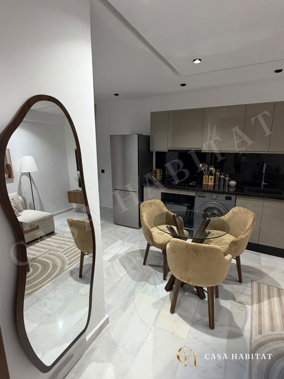 Coin repas avec table en verre, chaises beiges et miroir arrondi