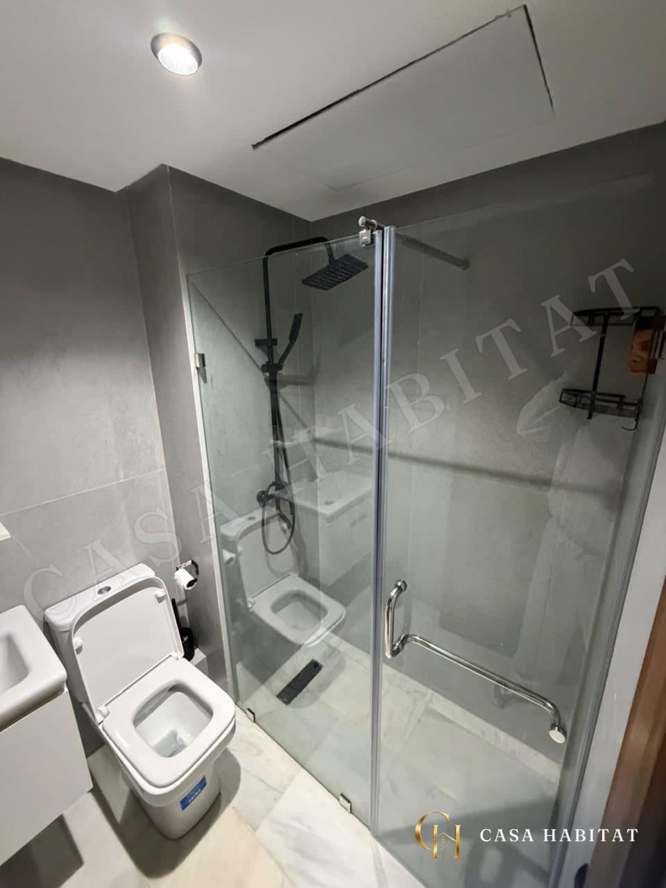 Salle de bain avec douche en verre, WC blancs et murs gris