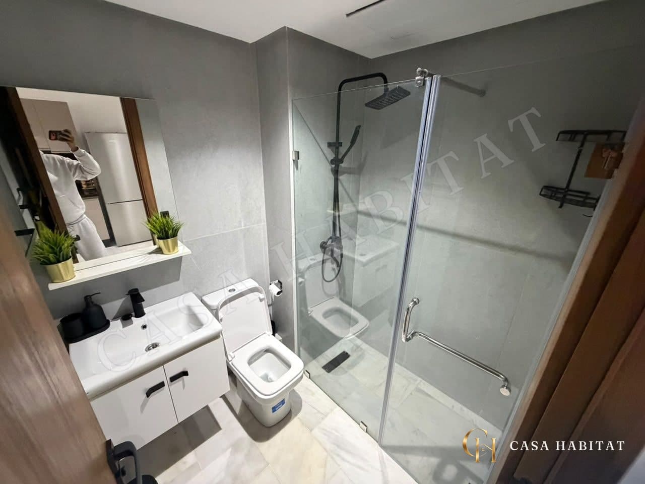 Salle de bain avec douche en verre, lavabo blanc et WC