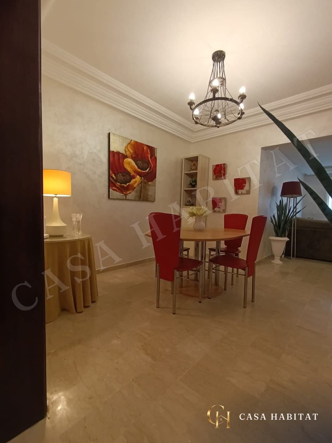 Salle à manger avec table ronde, chaises rouges et lustre en fer forgé