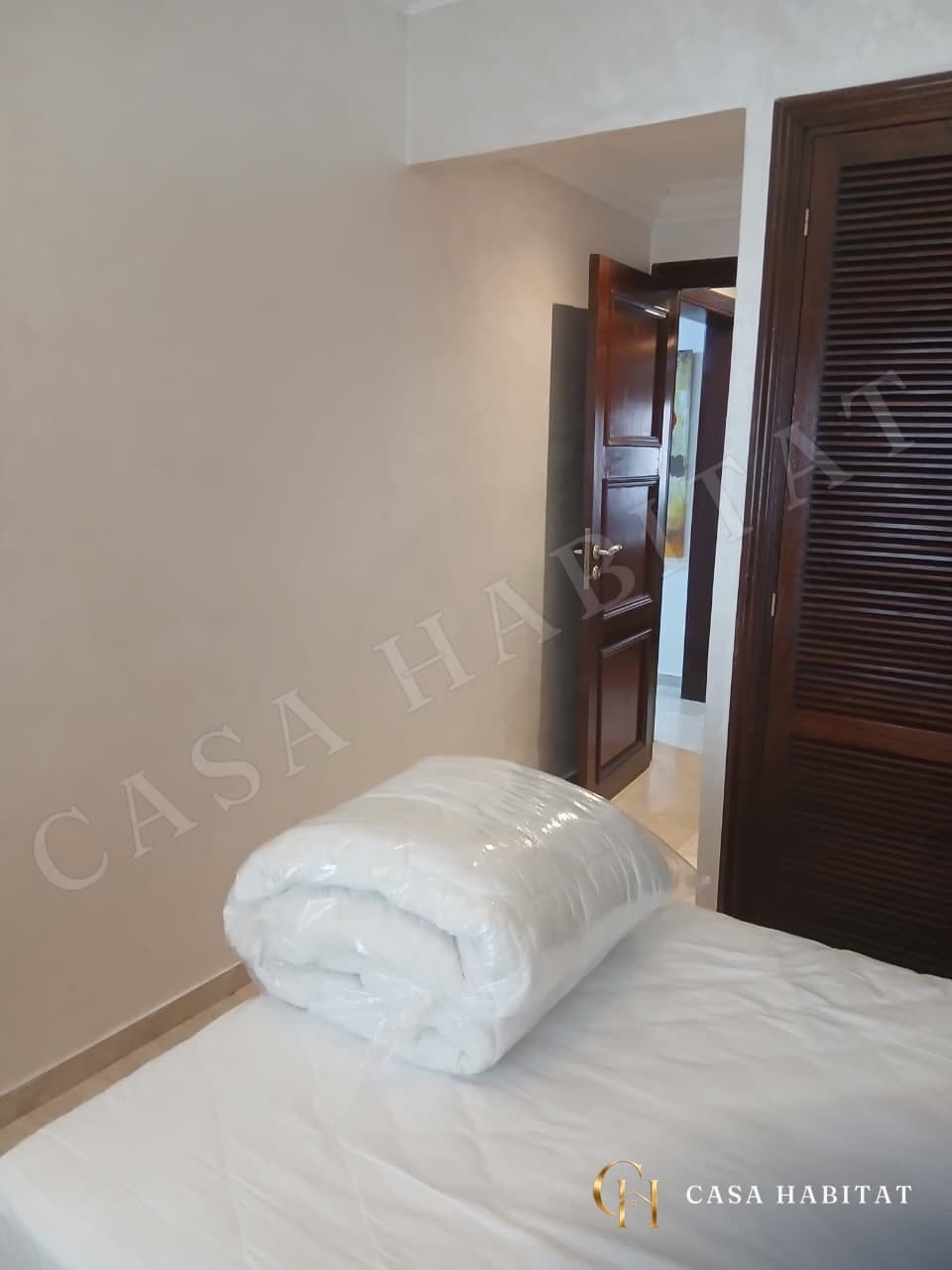 Couloir avec lit recouvert d'une couette sous plastique et porte en bois