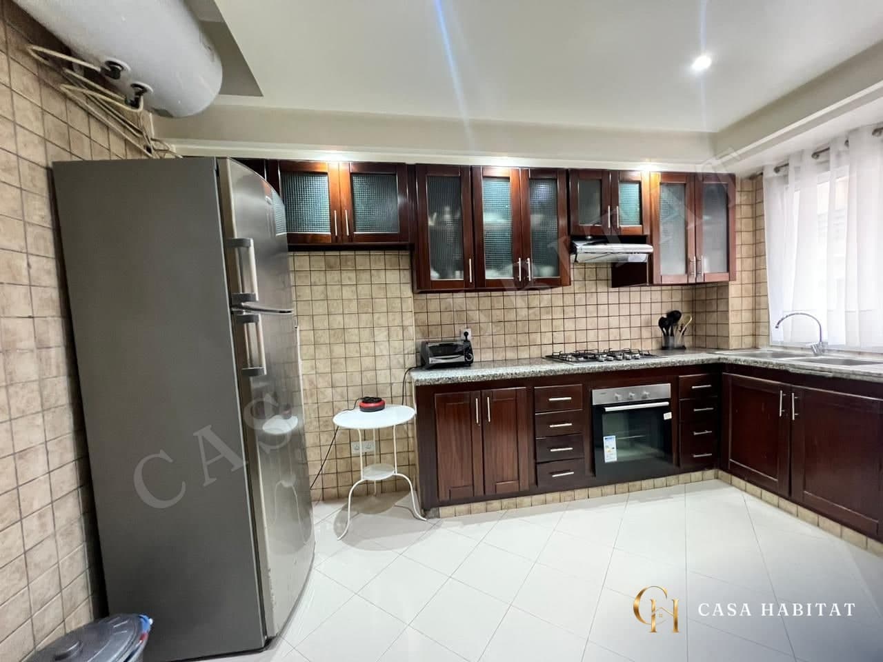 Cuisine en bois avec réfrigérateur inox, plaque de cuisson et fenêtre